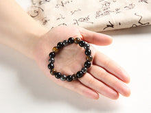 Load image into Gallery viewer, Beaded bracelet featuring hematite, tiger's eye, and obsidian stones on a hand.